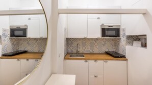 Una cocina pequeña con armarios blancos, un microondas y un lavamanos.
