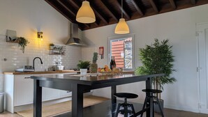 A modern kitchen with a central island, pendant lights, and a view of the outdoors. - Amazing 180° Ocean View 3 Bedroom Villa w/ Swimming Pool  (Capelo - Horta)