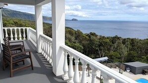 A balcony with a view of the sea and greenery, a wooden chair, and a small pool area. - Amazing 180° Ocean View 3 Bedroom Villa w/ Swimming Pool  (Capelo - Horta)