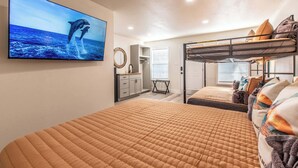 Ein Schlafzimmer mit Etagenbetten, einem Fernseher, der Delfine zeigt, einem Nachttisch und einem Fenster mit Jalousien.