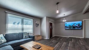 Ein Wohnzimmer mit einer Couch, einem Couchtisch und einem an der Wand montierten Fernseher.