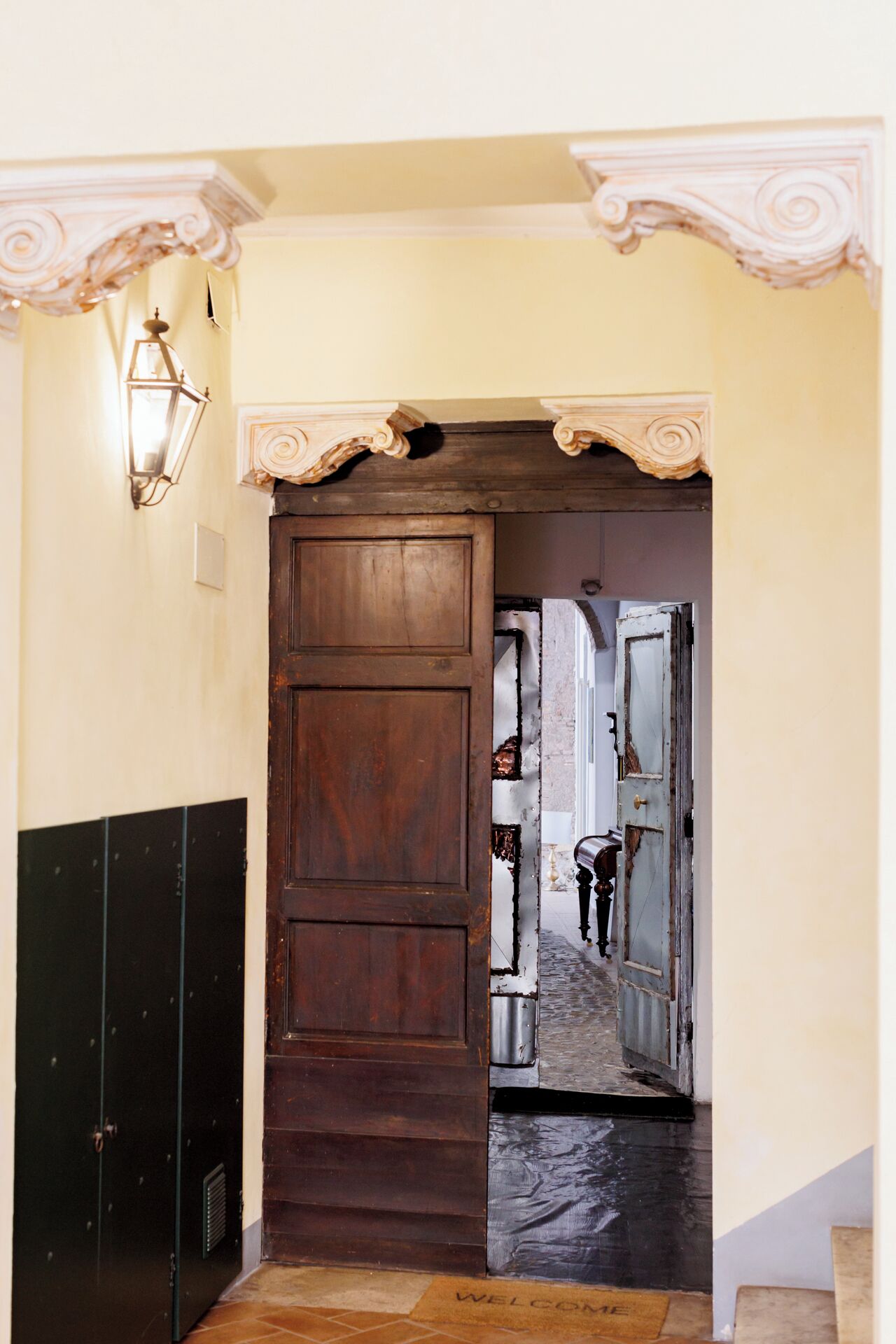 A hallway with a wooden door, a light fixture, and a metal door frame.