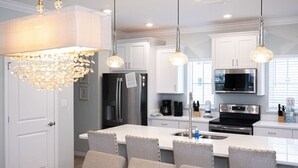 A modern kitchen with white cabinets, stainless steel appliances, and a central island with chairs. - 3 br, gulf view, beach club, pools, gym, hot tub (Pensacola)