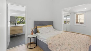 A bedroom with a bed, bedside table, and a view of the outside. - Beach View Cottage. Cosy with direct water views. (Clontarf)