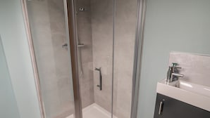 A modern bathroom with a glass-enclosed shower, a white sink, and a dark-toned cabinet. - ARD NA GHAOITHE, pet friendly in Loughanure, County Donegal (Loughanure)