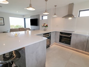 A modern kitchen with a central island, stainless steel appliances, pendant lighting, and a view to the outdoors.