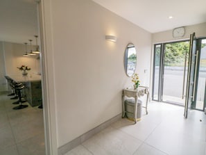 A clean, modern lobby with a reception desk, a mirror, and a clock on the wall.