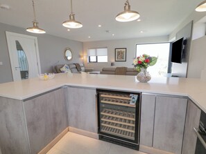 A modern kitchen with a built-in wine cooler, pendant lighting, and a large island.