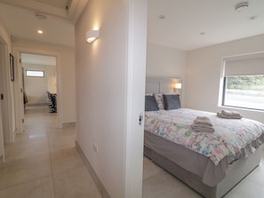 A bedroom with a bed, a window, and a bathroom visible in the background.