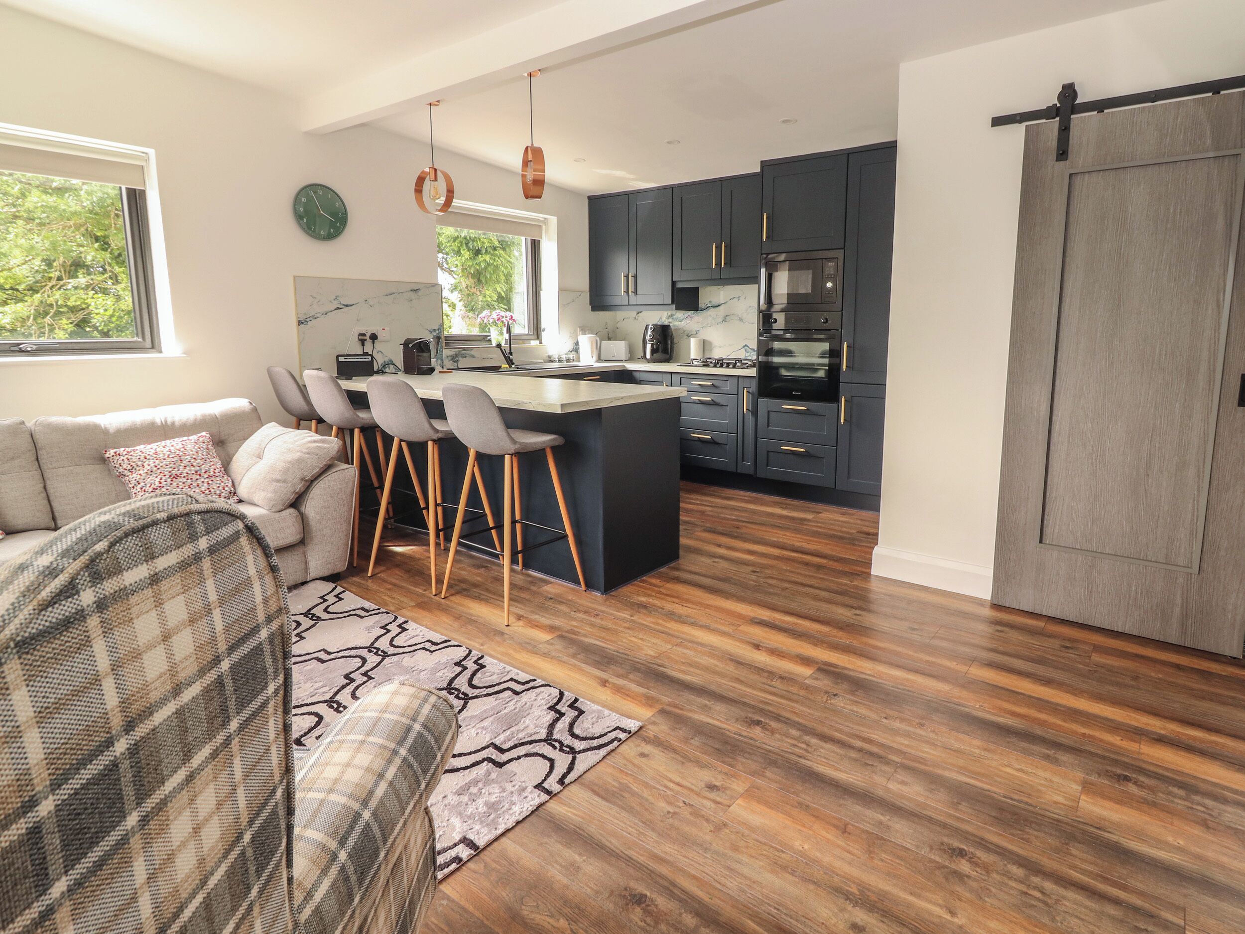 A modern kitchen with dark cabinets, a central island, and a sliding barn door.