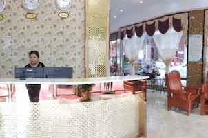 Una mesa de recepción con computadora, un reloj y un ventanal con cortinas.