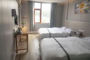 A hotel room with two beds, a wooden sideboard, a window with curtains, and a wall-mounted TV. - Hetianxia Hotel (Wuyuan)