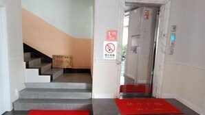 A staircase leading to an elevator with red mats at the bottom. - Hetianxia Hotel (Wuyuan)