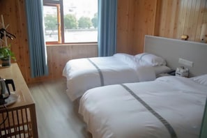 Habitación de hotel con dos camas, cabecero de madera, escritorio con hervidor y ventana con cortinas.