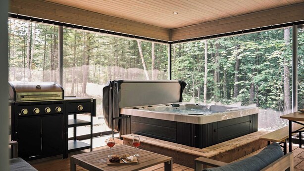 A covered outdoor area with a grill, hot tub, seating, and a table with snacks. - Chalet Nova - Spa, Sauna & in the Nature (Chertsey)