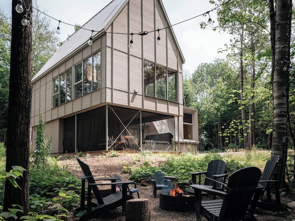 Una casa moderna con ventanas amplias, una terraza y asientos exteriores.