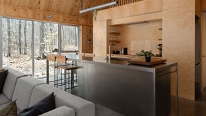A modern kitchen with a central island, wooden ceiling, and large windows overlooking a forest. - Chalet Nova - Spa, Sauna & in the Nature (Chertsey)
