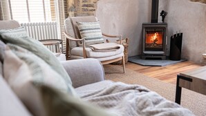 A cozy living room with a sofa, armchair, and a fireplace. - A spectacular barn conversion - Highgate (Moreton-in-Marsh)