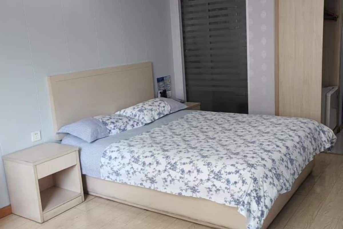 Egy hálószoba, amelyben van egy ágy, egy éjjeliszemélyzet, egy ablak, amelyen redőny van, és egy ajtó.