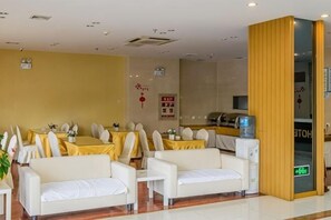 A hotel dining area with white sofas, yellow tablecloths, and a water dispenser. - Huacheng Express Hotel (Jiangyin)