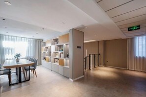 A modern hotel room with a dining area, built-in shelving, and a staircase.