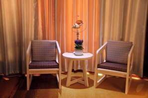 Two chairs with cushions, a small round table with a vase of flowers, and a decorative item on the table. - Xixiana Aisi Concept Hotel (Xixia)