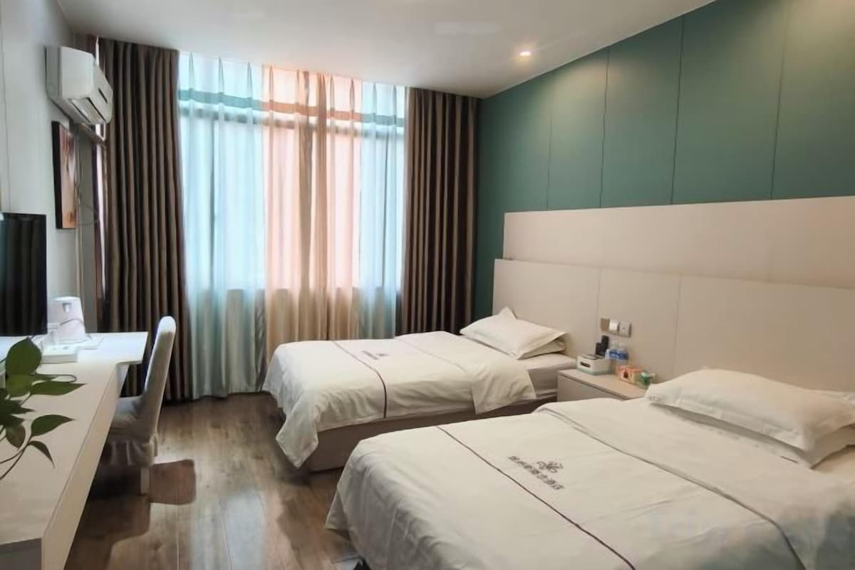 A hotel room with two beds, a desk, and a chair.