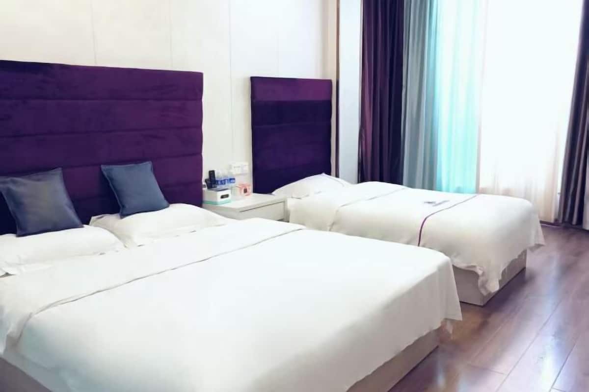 Habitación de hotel con dos camas, una mesita de noche y una ventana con cortinas.