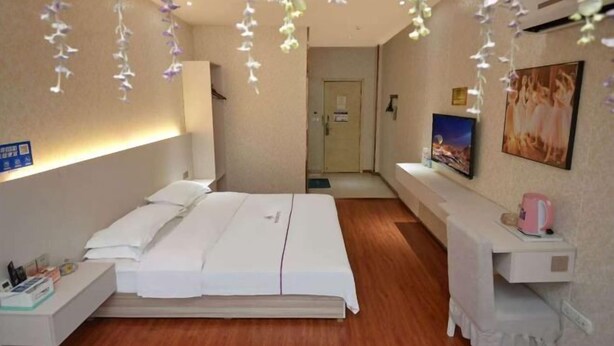 Une chambre d’hôtel avec un lit, une table de chevet et un téléviseur fixé au mur.