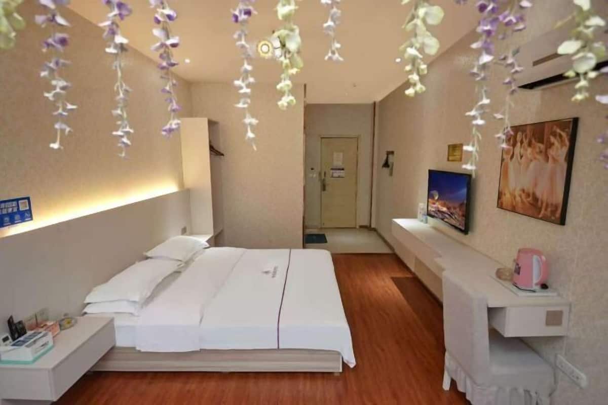 Una habitación de hotel con cama, mesita de noche y televisor montado en la pared.