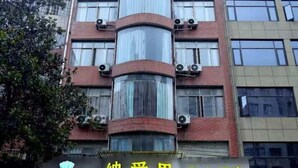 La façade d’un hôtel, avec un ascenseur à cage vitrée au centre, de nombreuses fenêtres et des unités de climatisation.