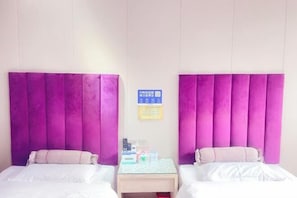 A hotel room with two beds, a small bedside table, and a sign on the wall.
