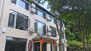 A building with multiple windows, air conditioning units, and a traditional-style entrance with a tiled roof and red lanterns. - Hengyang Nanyue Hengshan Qingshan Yunju (Hengyang)