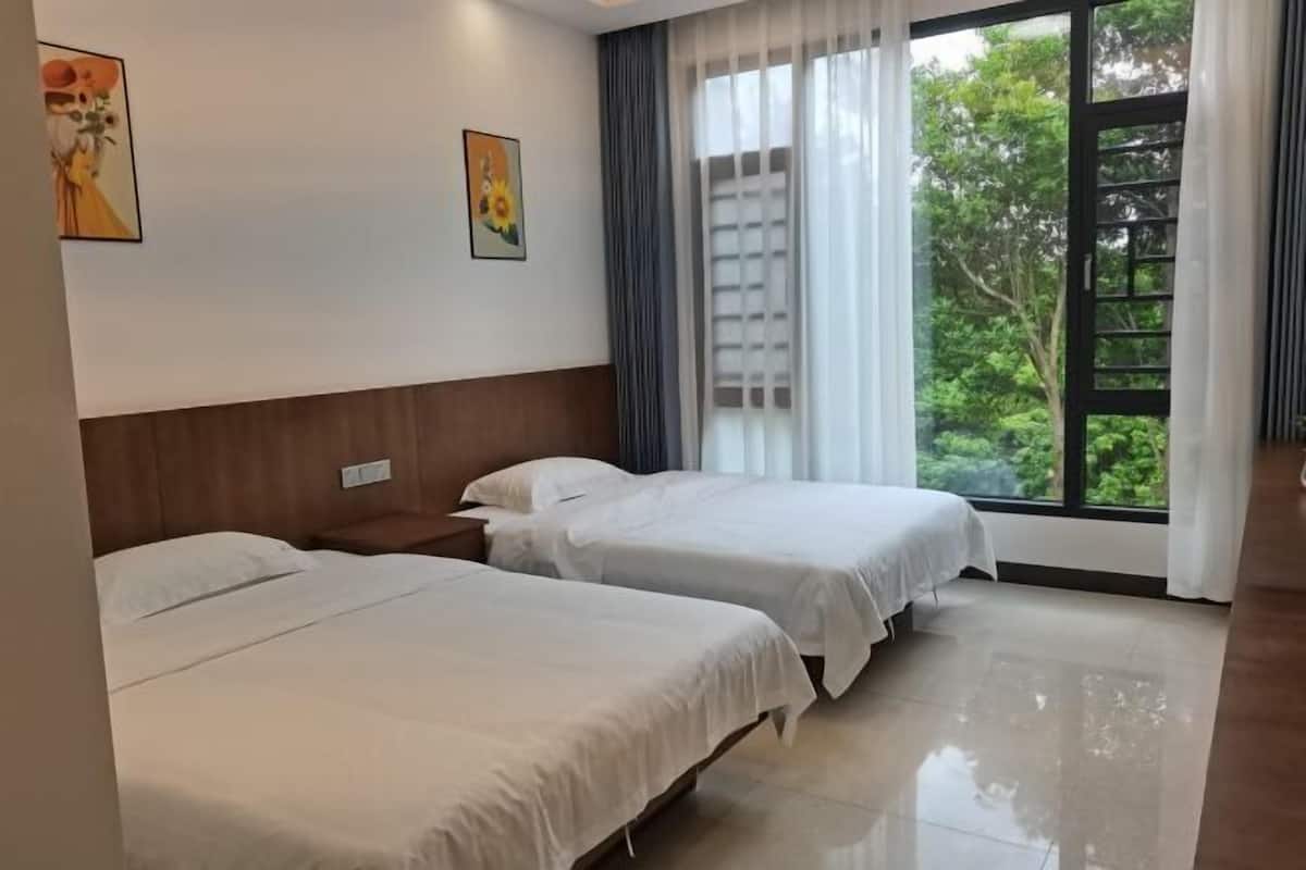 Quarto de hotel com duas camas, janela com cortinas e obras de arte nas paredes.