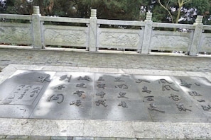 A stone plaque with engraved text, a stone fence with decorative elements, and a paved walkway. - Hengyang Nanyue Hengshan Qingshan Yunju (Hengyang)