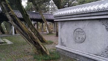 Un monumento de piedra con caracteres chinos tradicionales, rodeado por una estructura de techo de tejas y árboles.