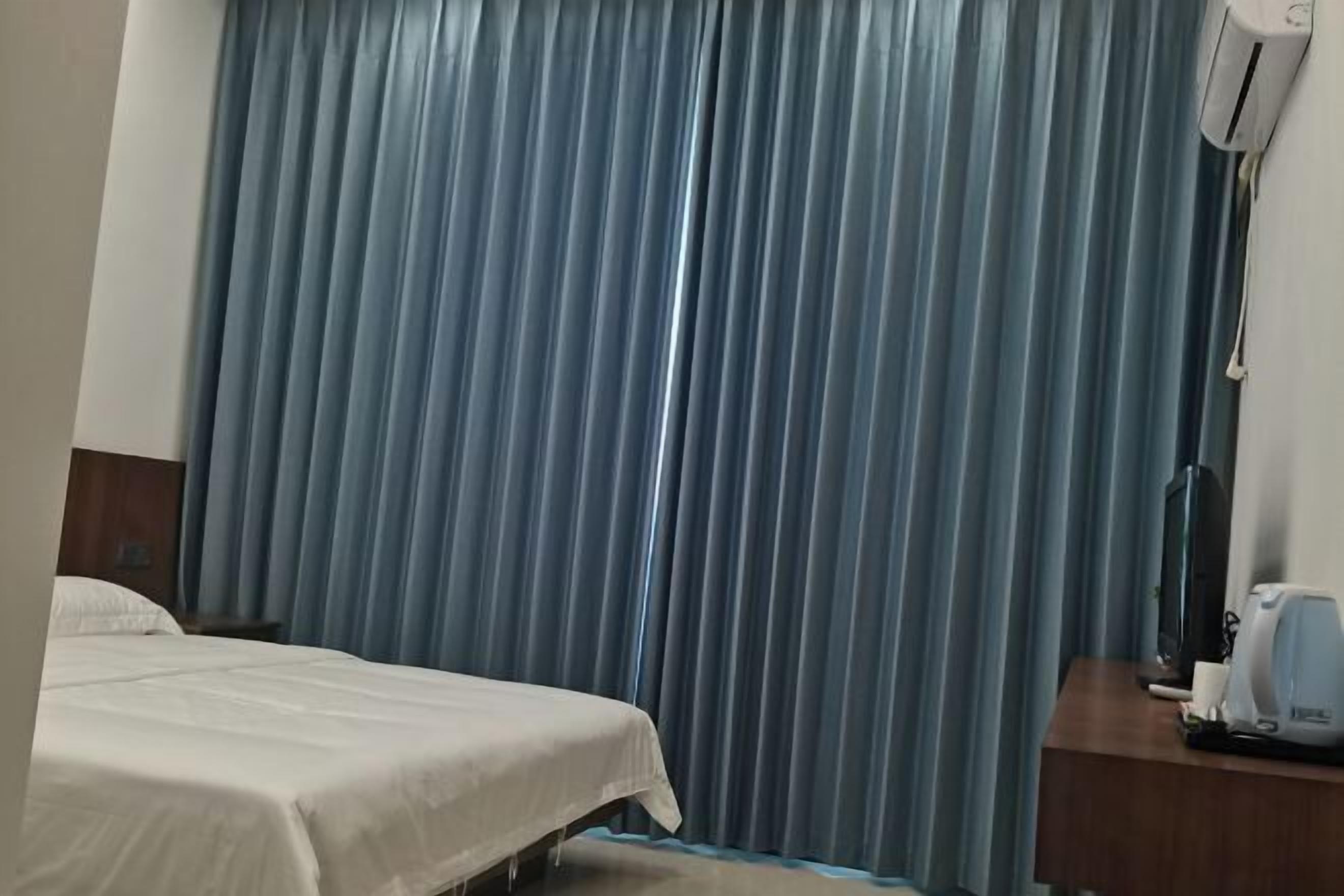 Una habitación de hotel con cama, escritorio con cafetera y aire acondicionado de pared.