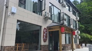 A building with a large glass window, a wooden bench outside, and a traditional red lantern. - Hengyang Nanyue Hengshan Qingshan Yunju (Hengyang)