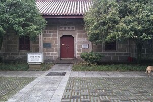Un edificio tradicional con puerta roja, paredes de piedra y tejado de baldosas.