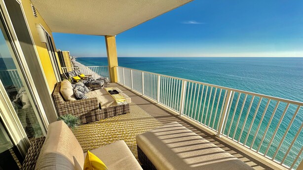 Un balcon avec vue sur l’océan, aménagé avec des canapés et des coussins en osier, et un tapis à motifs.