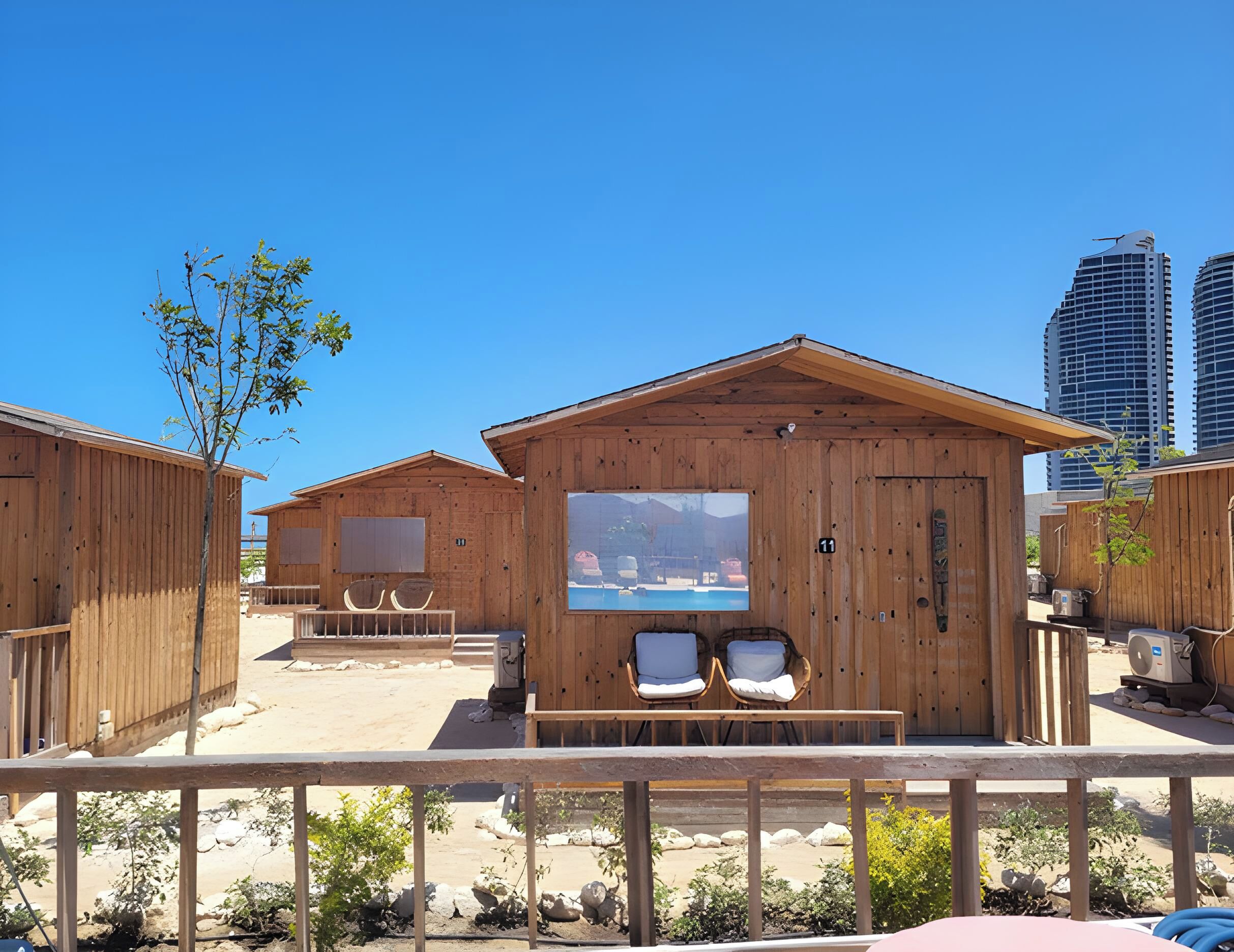 Des cabanes en bois équipées de deux chaises et d’une fenêtre, avec une piscine et une vue sur la montagne.