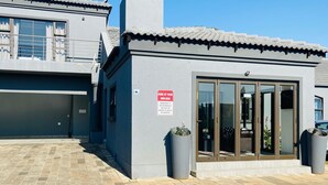 A building with a garage door, a small entrance with glass doors, and a sign indicating parking at your own risk.
