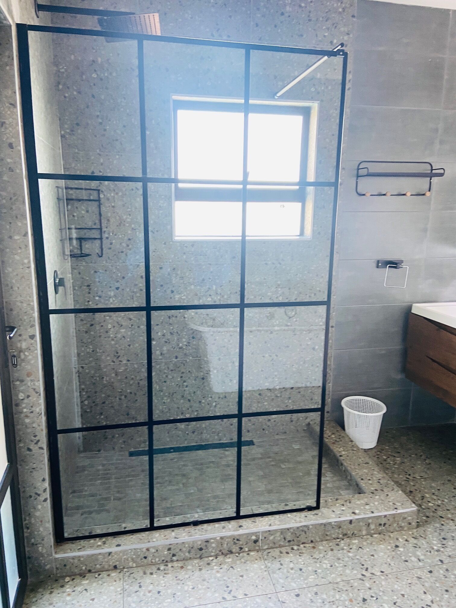 A shower enclosure with a frosted glass door, a small window, and a metal towel rack.