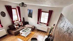 Ein großzügiges Wohnzimmer mit einem braunen Ledersofa, einem Glastisch und einem Essbereich mit Tisch und Stühlen.