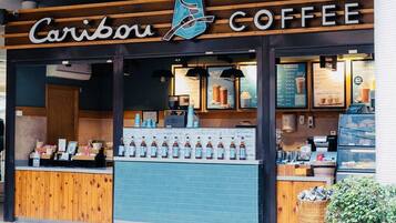 Caribou Coffee -niminen kahvila, jonka julkisivu on puuta, siinä on sinisillä laatoilla koristeltu seinä ja esillä on pulloihin pakattuja juomia.