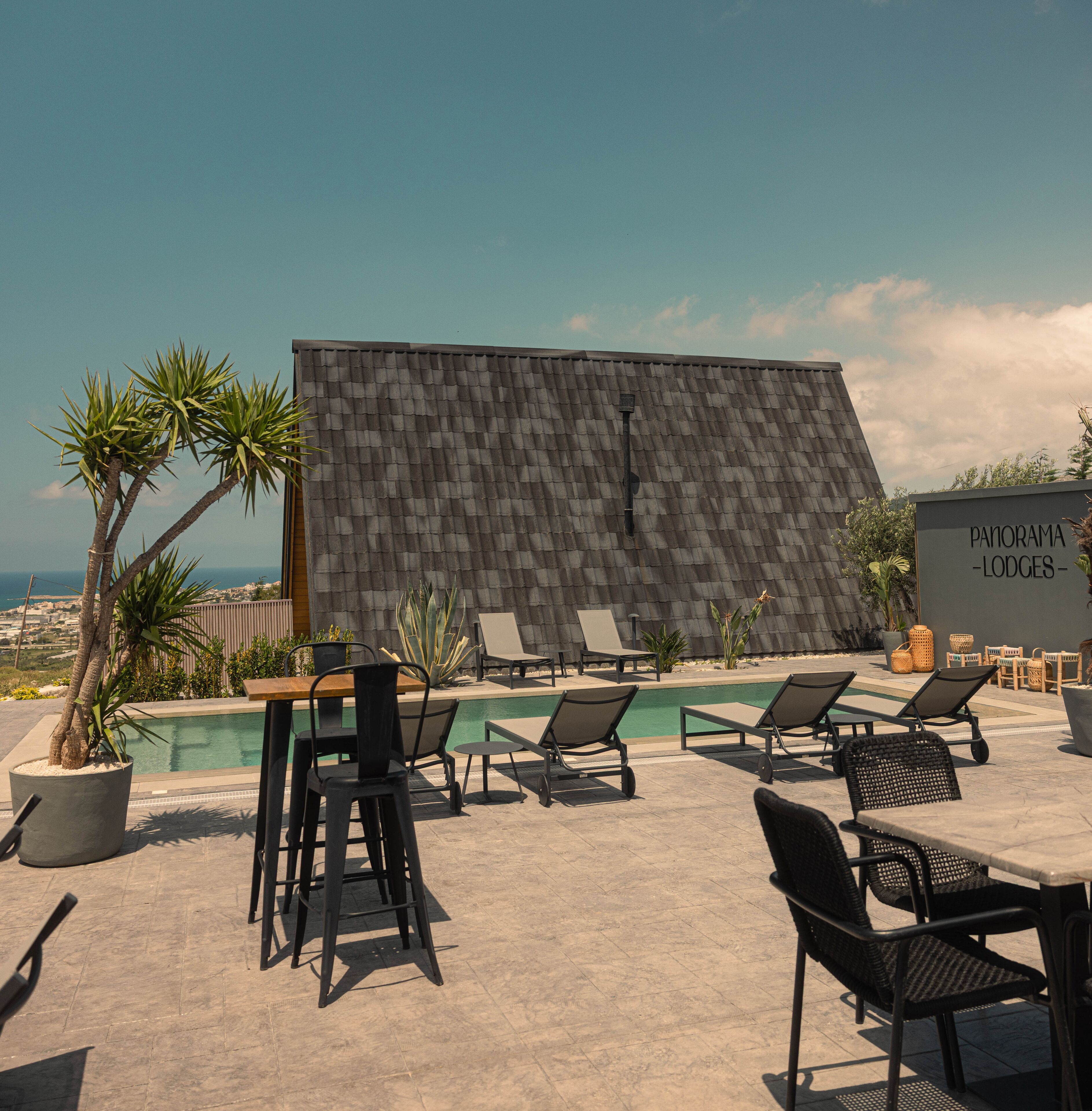 A rooftop pool area with lounge chairs and a sign reading "PANORAMA - LODGES -".