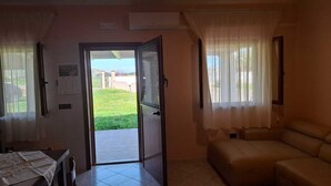 Une pièce dotée d’une porte coulissante donnant sur un balcon, d’un canapé et d’une table sur laquelle se trouvent des papiers.