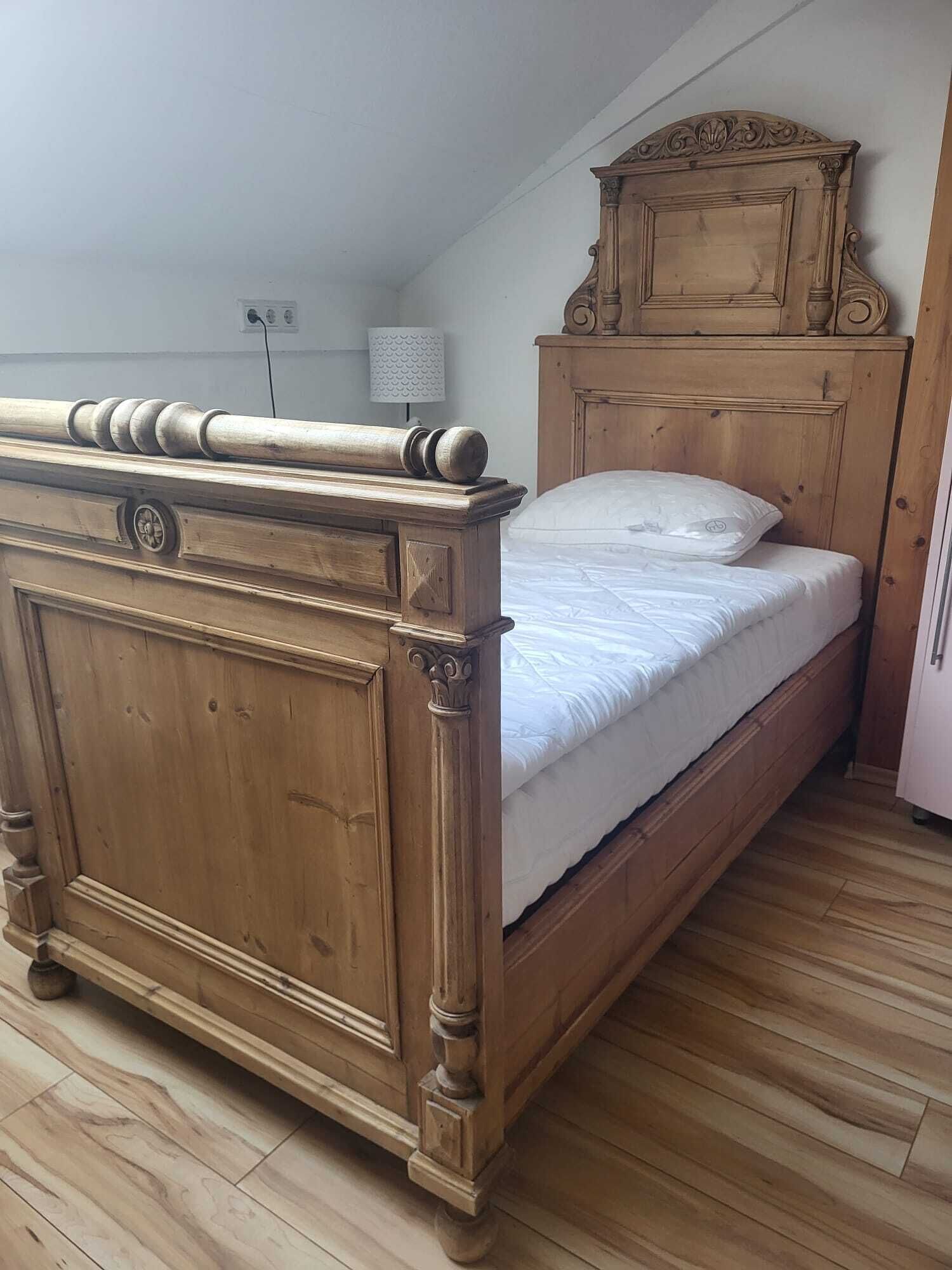 Ein hölzernes Bett mit Kopfteil und Fußteil, ein Nachttisch und eine Lampe auf Holzboden.