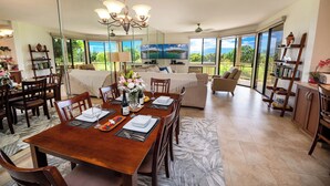 A spacious dining area with a wooden table set for four, a large mirror, and a view of the outdoors.