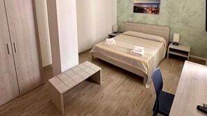 Una habitación de hotel moderna con cama, escritorio, silla, armario y equipo de aire acondicionado.